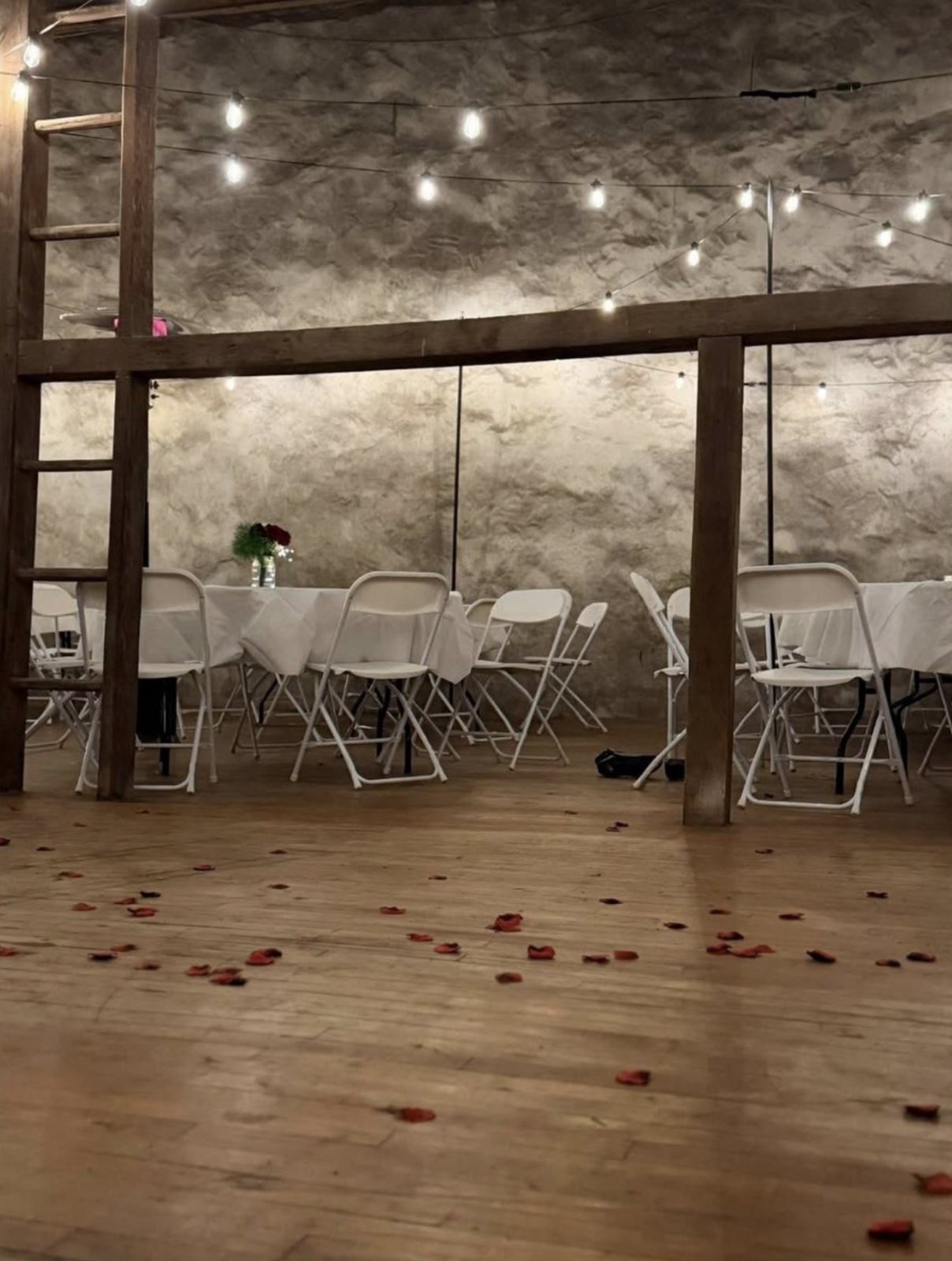 Tables set in the barn's stone-walled lower level, rose petals on the floor